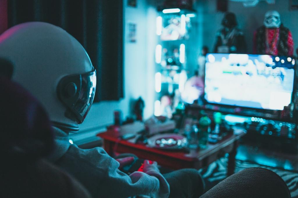 An astronaut playing video games and chilling in a dusky room